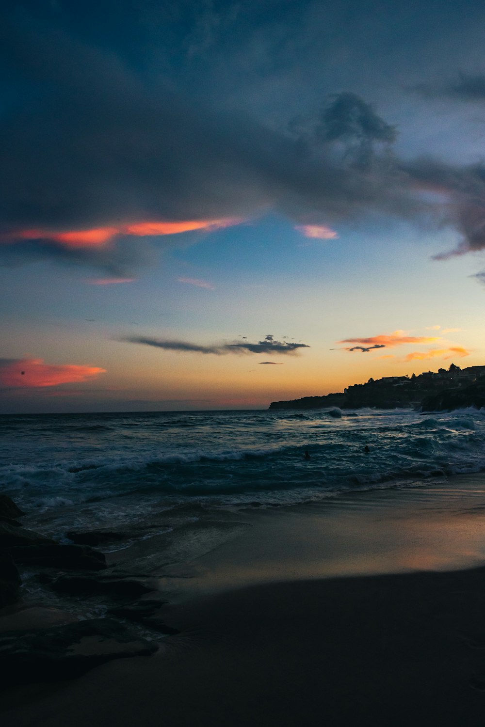 a beach at sunset with waves coming in to shore