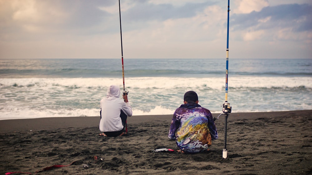 a couple of people sitting on top of a sandy beach