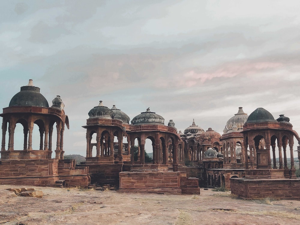 a group of stone structures sitting on top of a dirt field