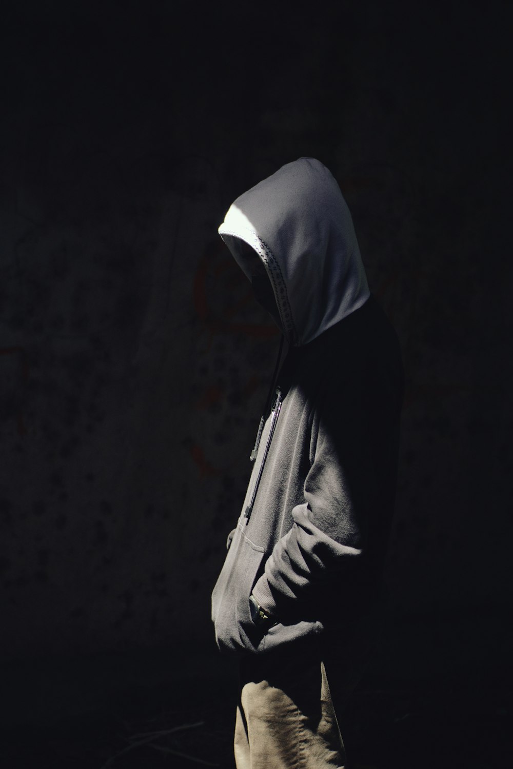 a person in a hoodie walking in the dark