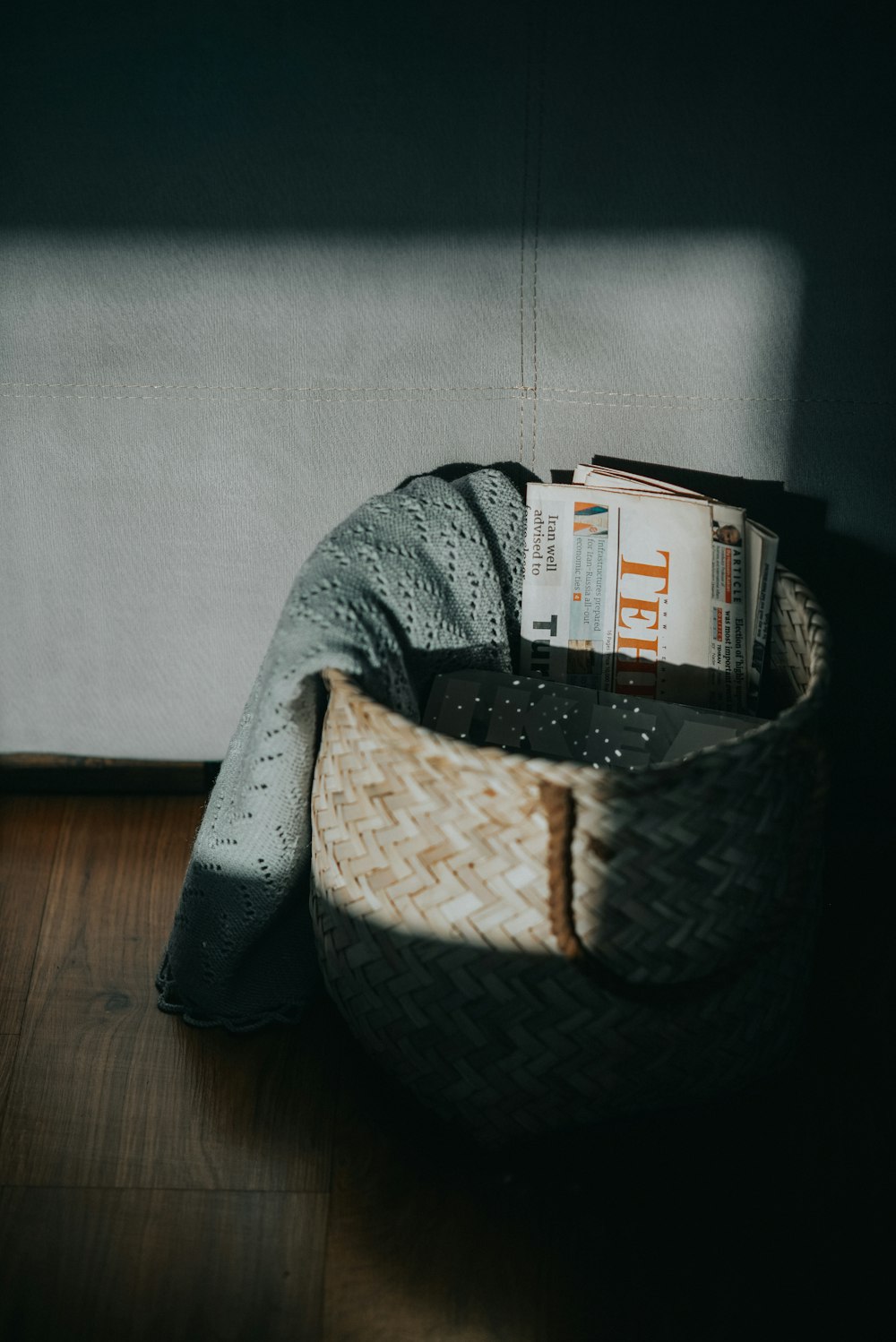 a basket filled with books sitting on top of a wooden floor