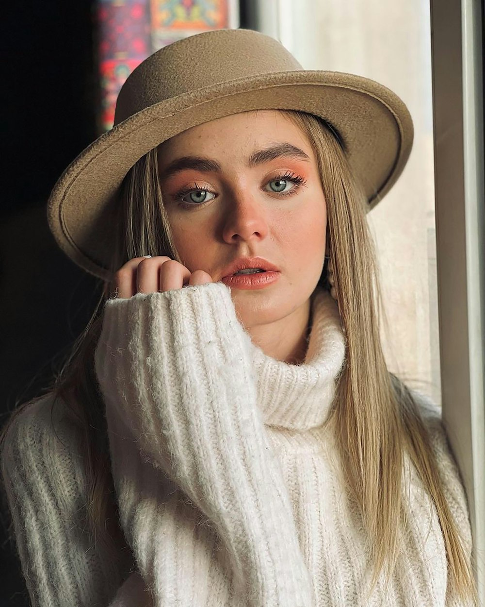 a woman wearing a hat and a white sweater