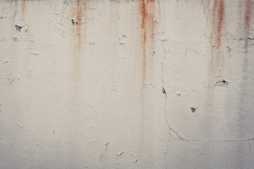 a white wall with rusted paint on it