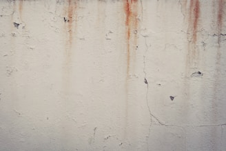 a white wall with rusted paint on it