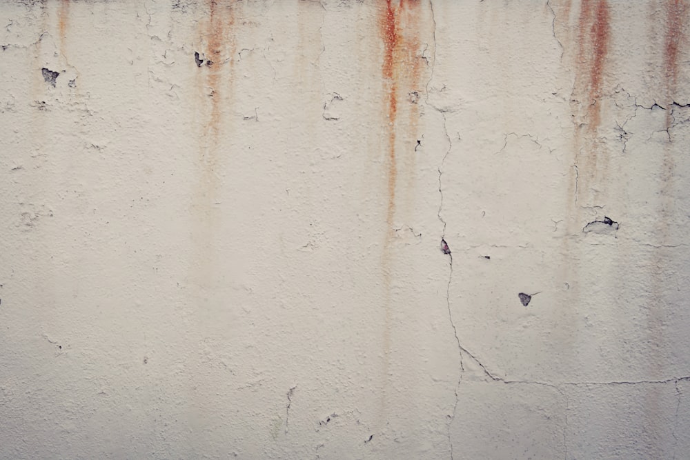 a white wall with rusted paint on it