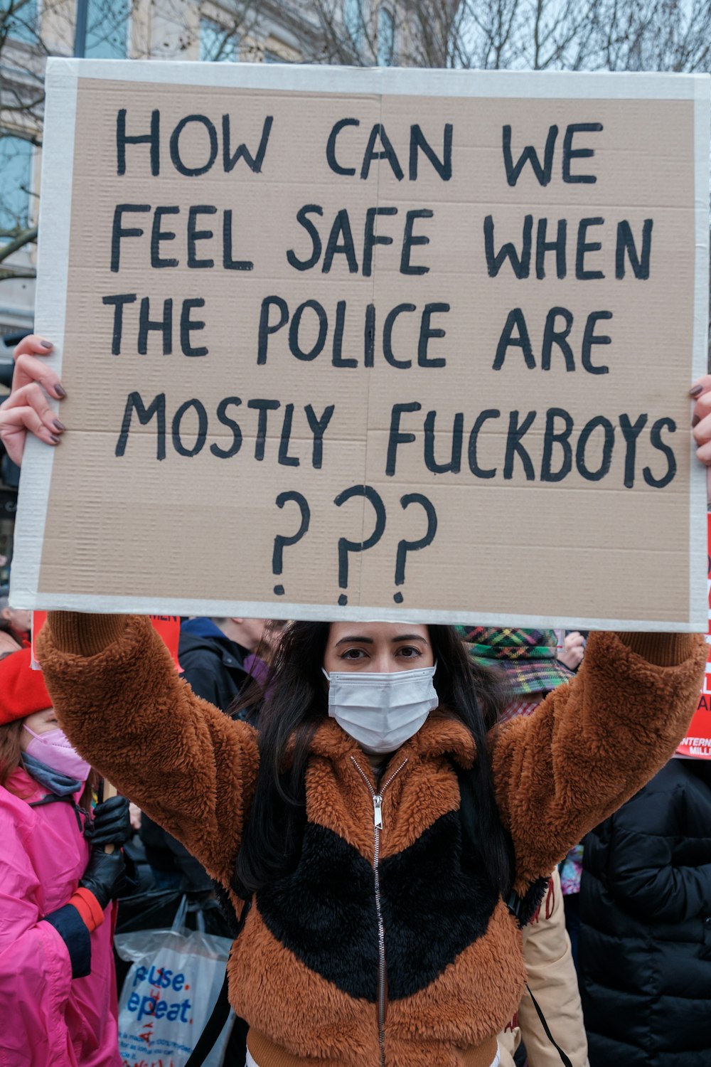 Una donna che tiene un cartello che dice come possiamo sentirci al sicuro quando la polizia è