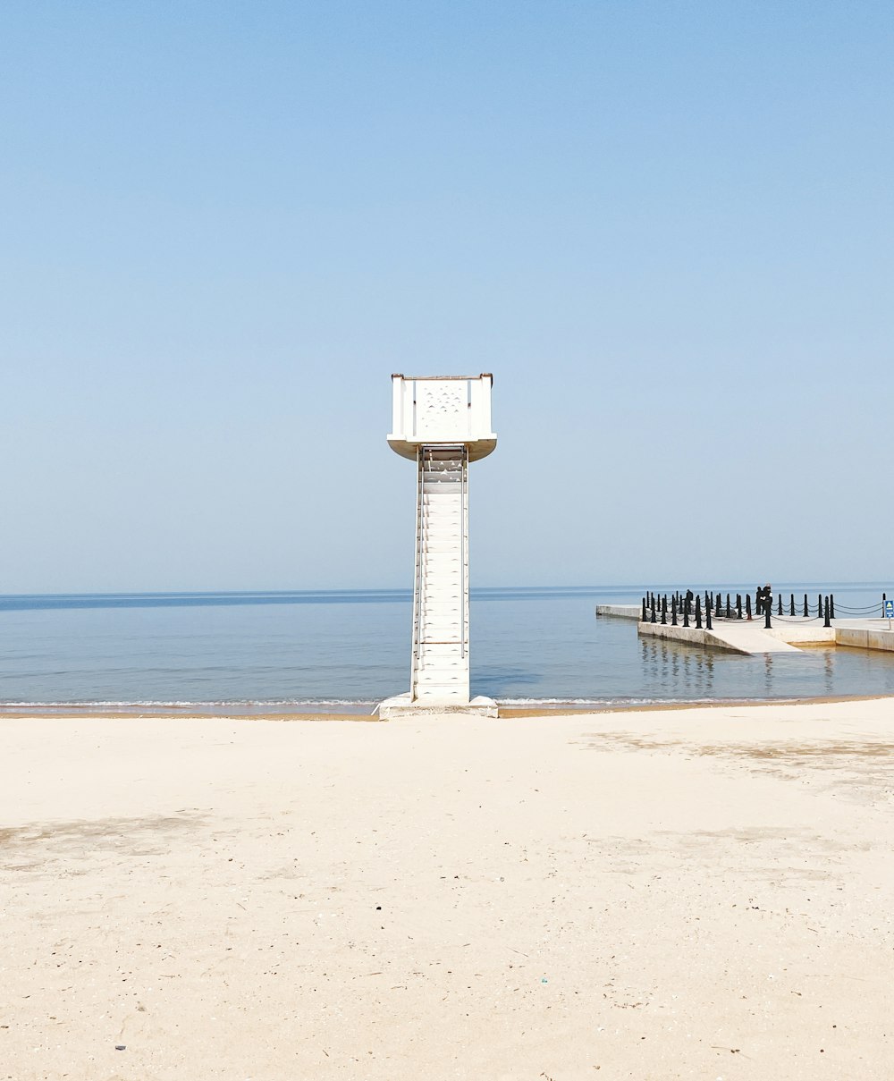 a white tower sitting on top of a sandy beach