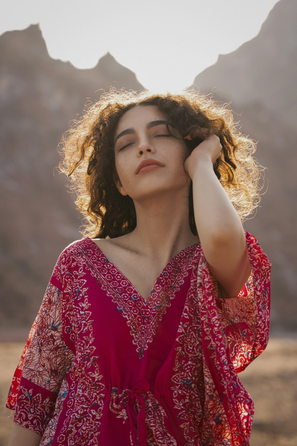 a woman in a red dress standing in front of a mountain