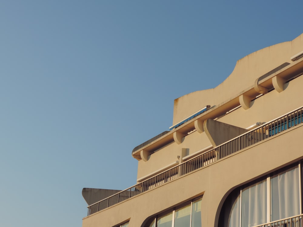 a tan building with balconies and a blue sky