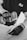 A black and white image captures a person wearing gloves using a power drill. The focus is on the hands and the drill, suggesting a construction or woodworking activity. The person is wearing a shirt with a logo on it.