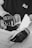 A black and white image captures a person wearing gloves using a power drill. The focus is on the hands and the drill, suggesting a construction or woodworking activity. The person is wearing a shirt with a logo on it.