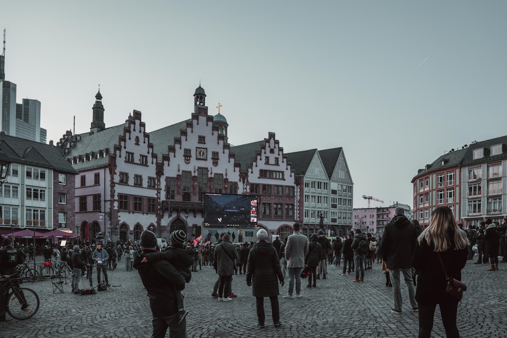 a crowd of people walking around a cobblestone street