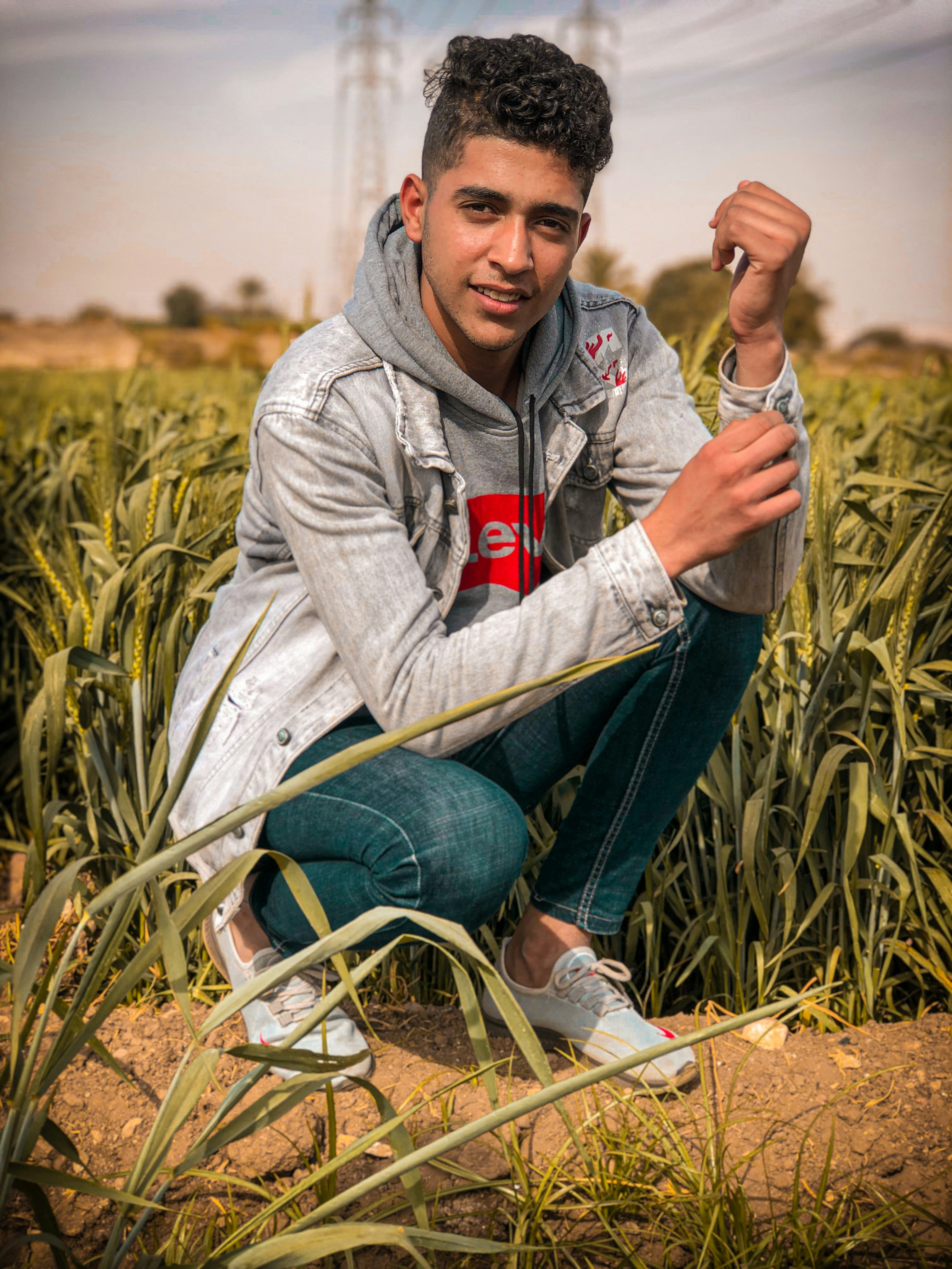 a young man squatting in a field holding an umbrella