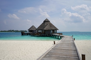 a pier leading to a beach with a hut on it
