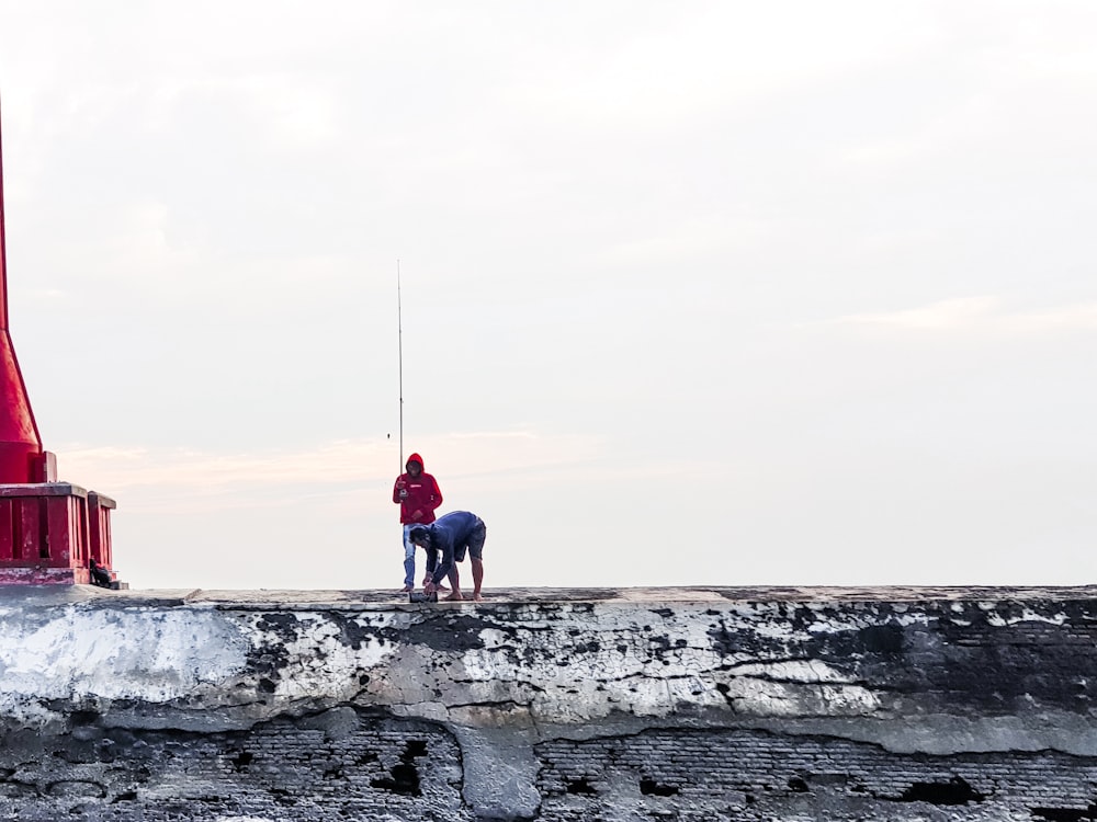 two people standing on a ledge with a dog