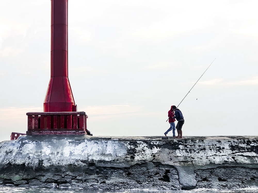 a man standing on top of a pier holding a fishing pole