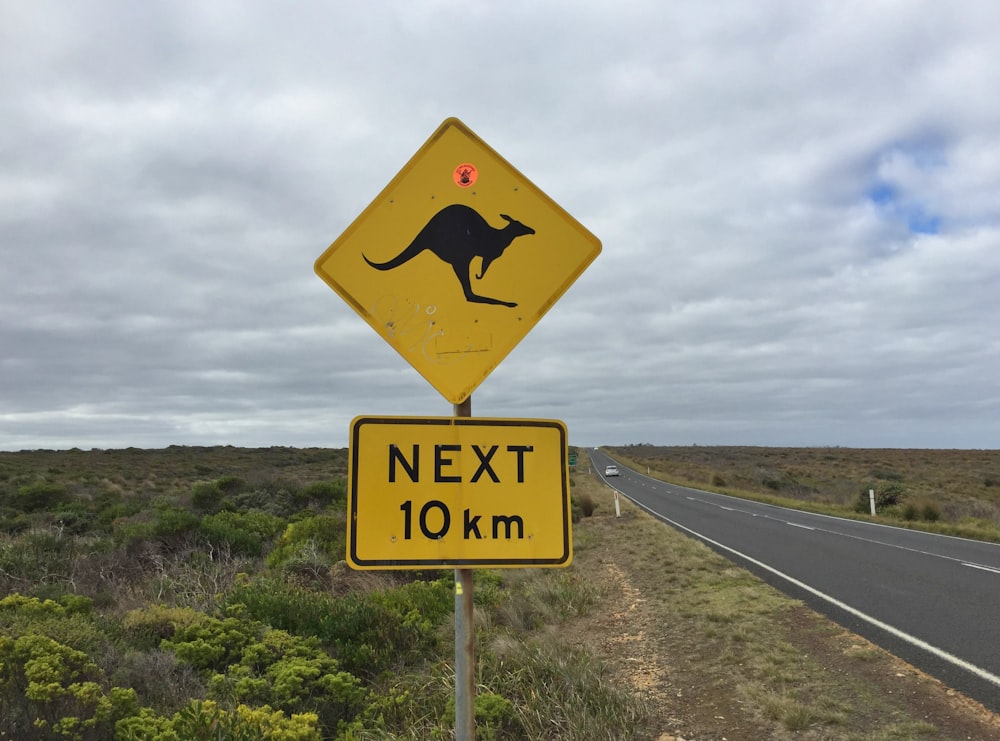a yellow kangaroo crossing sign on the side of a road