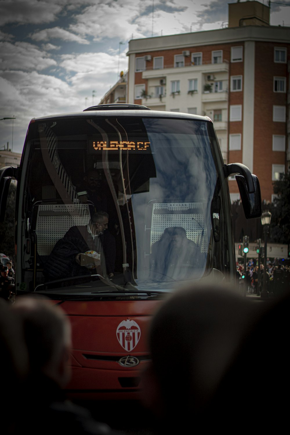 a red bus driving down a street next to tall buildings