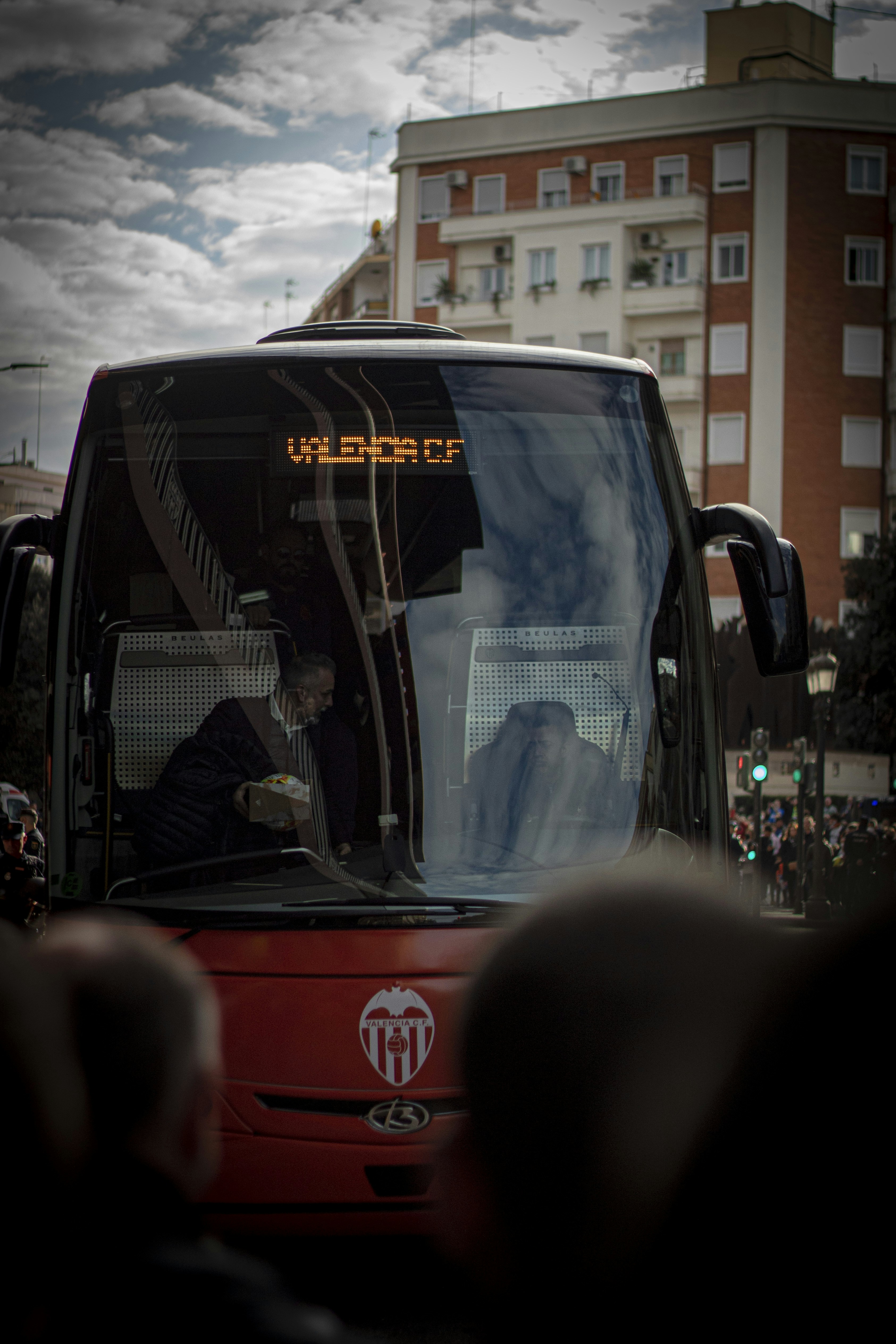a red bus driving down a street next to tall buildings