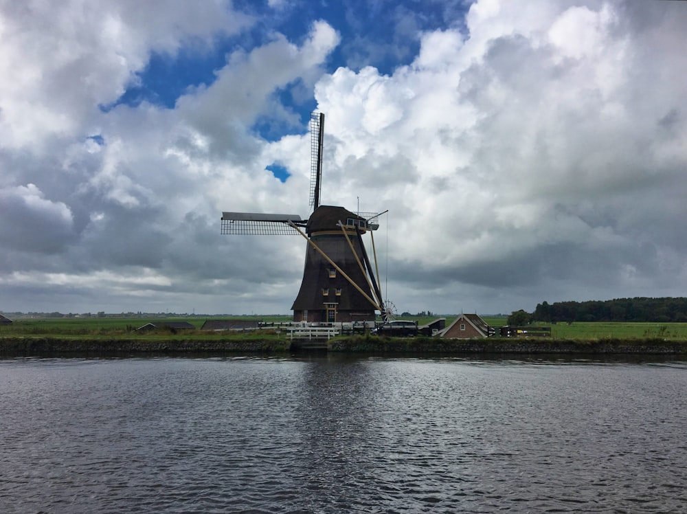 a large windmill sitting on the side of a river