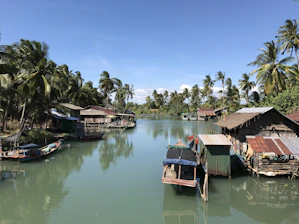 A peaceful riverside view with traditional wooden houses and children playing nearby.