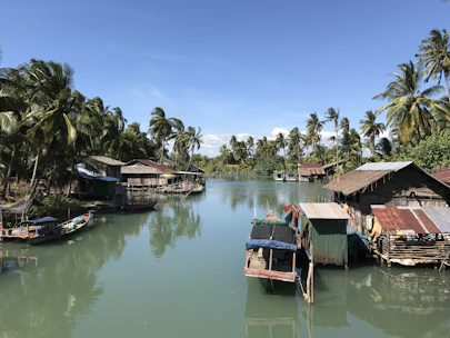 A peaceful riverside view with traditional wooden houses and children playing nearby.
