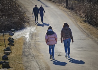 a couple of people walking down a dirt road