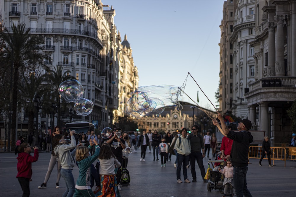 a crowd of people walking down a street next to tall buildings