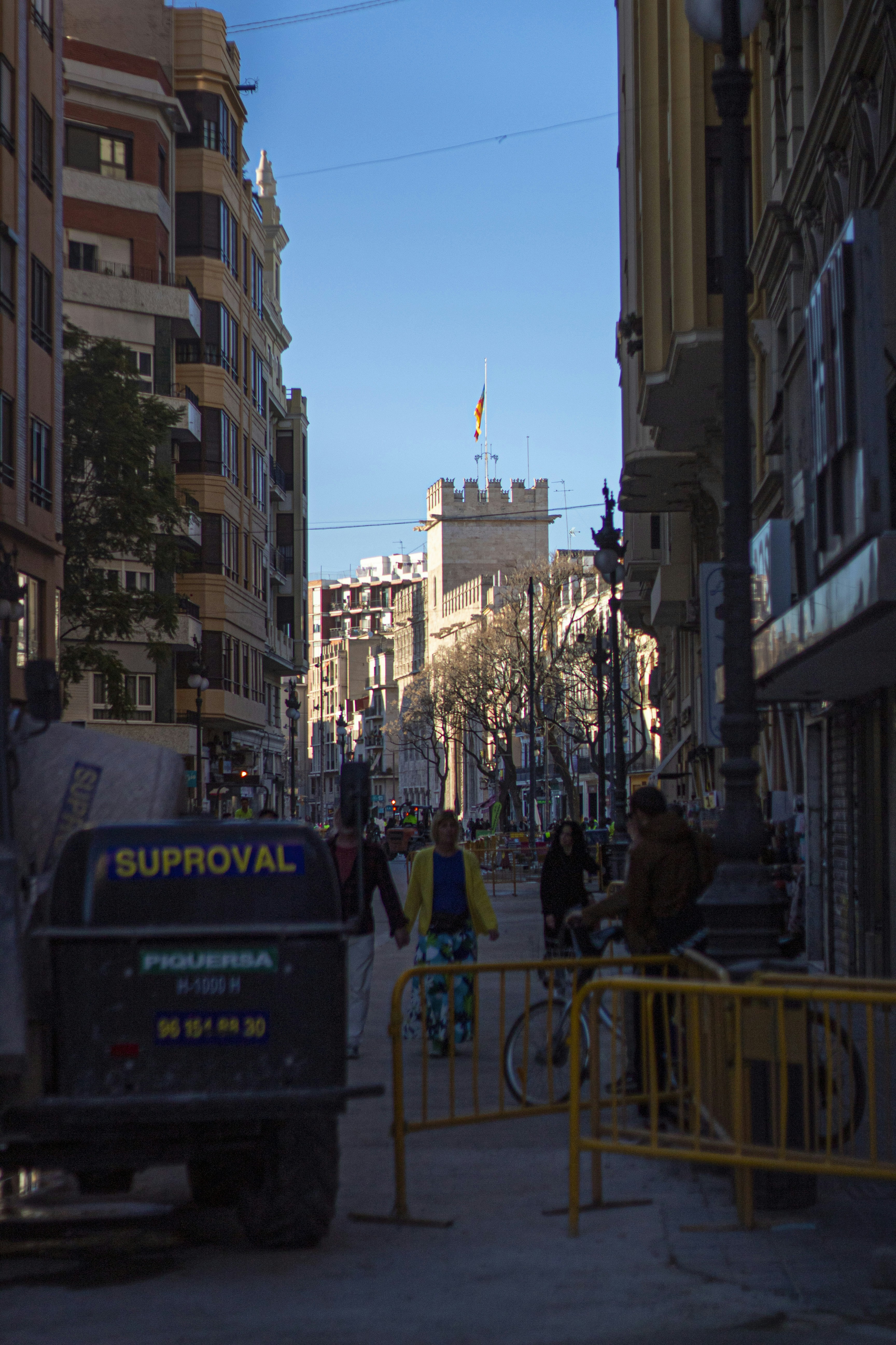 Un grupo de personas caminando por una calle junto a edificios altos