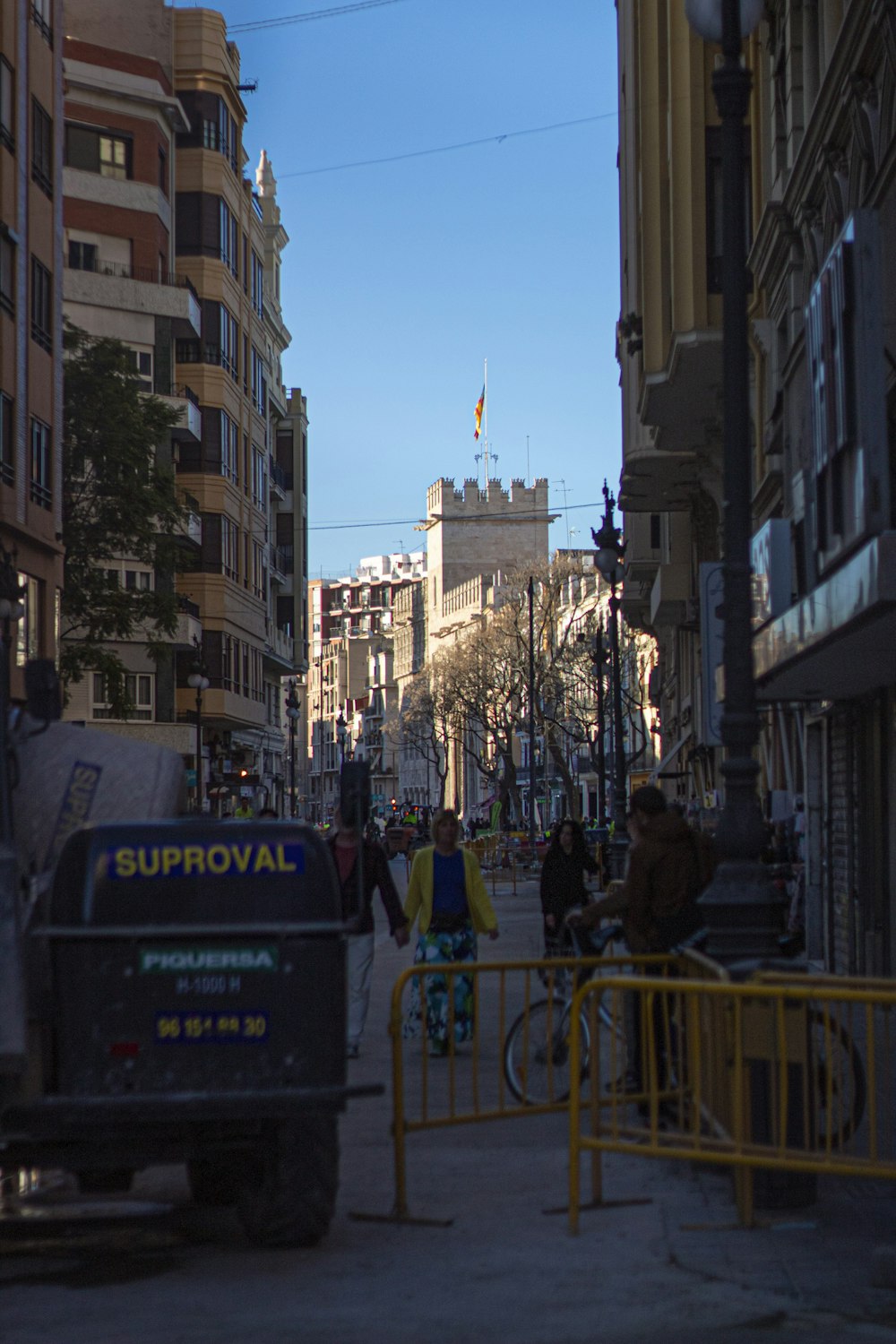 a group of people walking down a street next to tall buildings