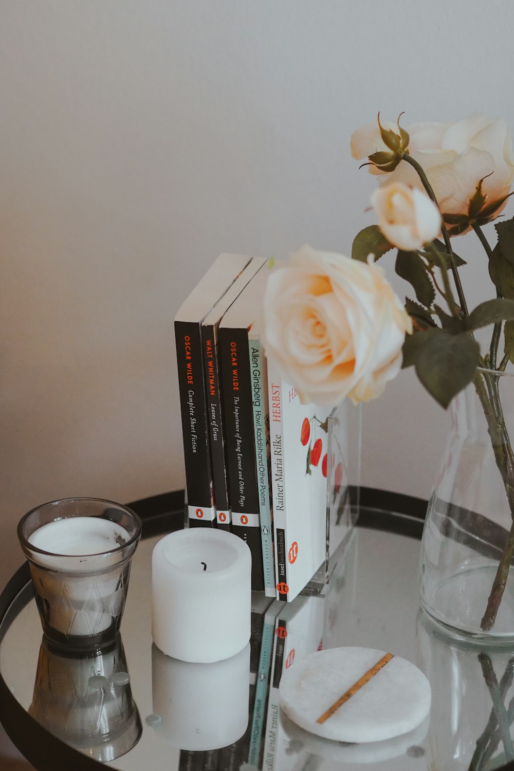 a glass table topped with books and a vase filled with flowers