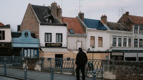 a man standing on a sidewalk in front of a row of buildings