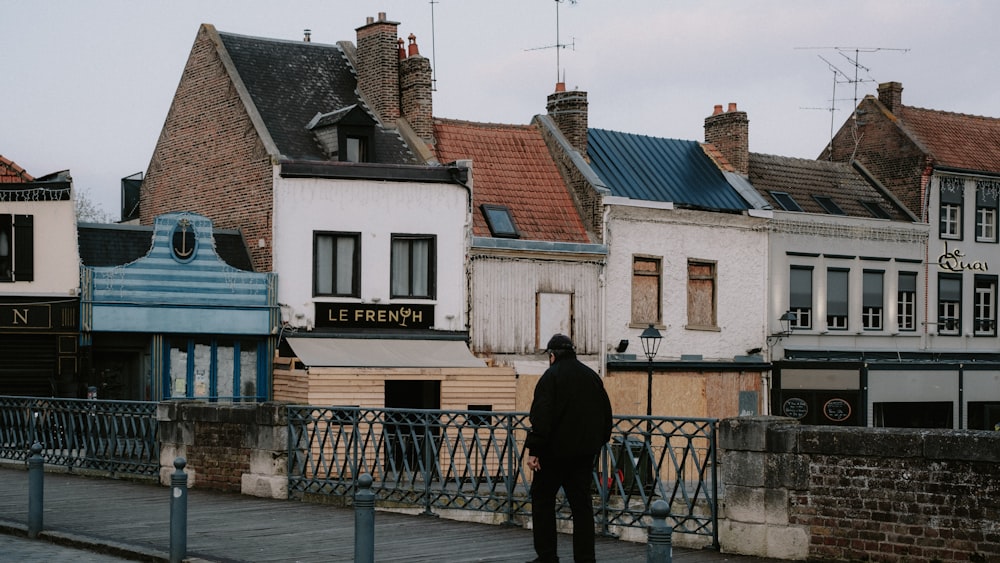 a man standing on a sidewalk in front of a row of buildings