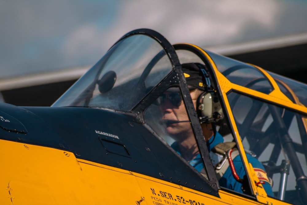 a man sitting inside of a yellow fighter jet