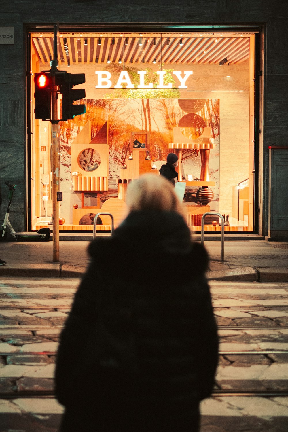 a woman walking down a street past a store front