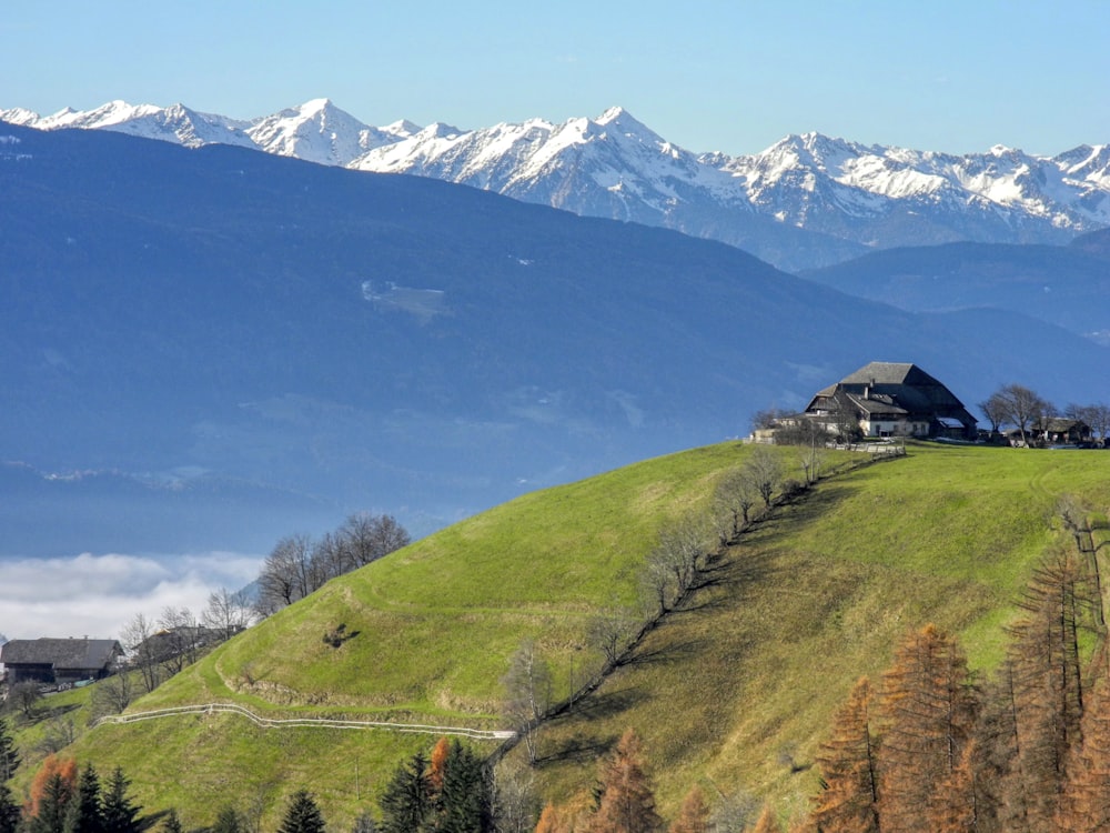 a house on a green hill with mountains in the background