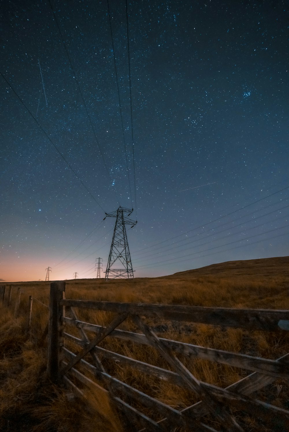 a wooden fence sitting in the middle of a field under a night sky