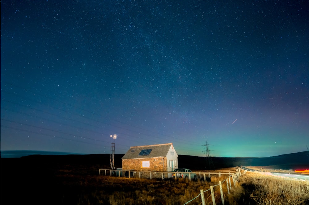 a house sitting on the side of a road under a night sky