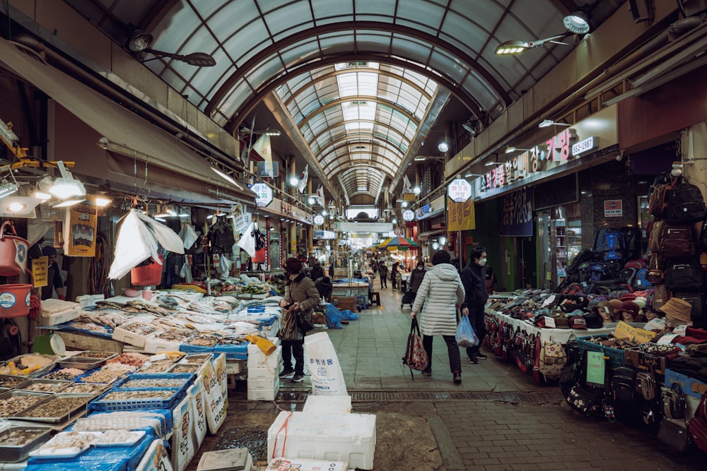a woman walking through a market filled with lots of food