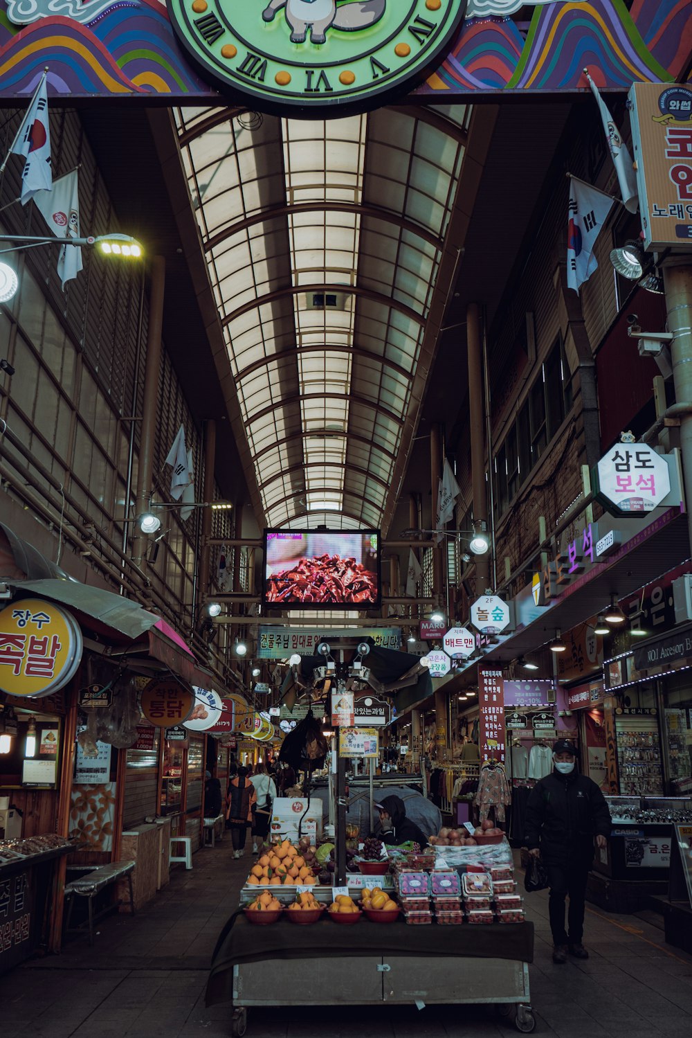 a market with a large clock hanging from the ceiling