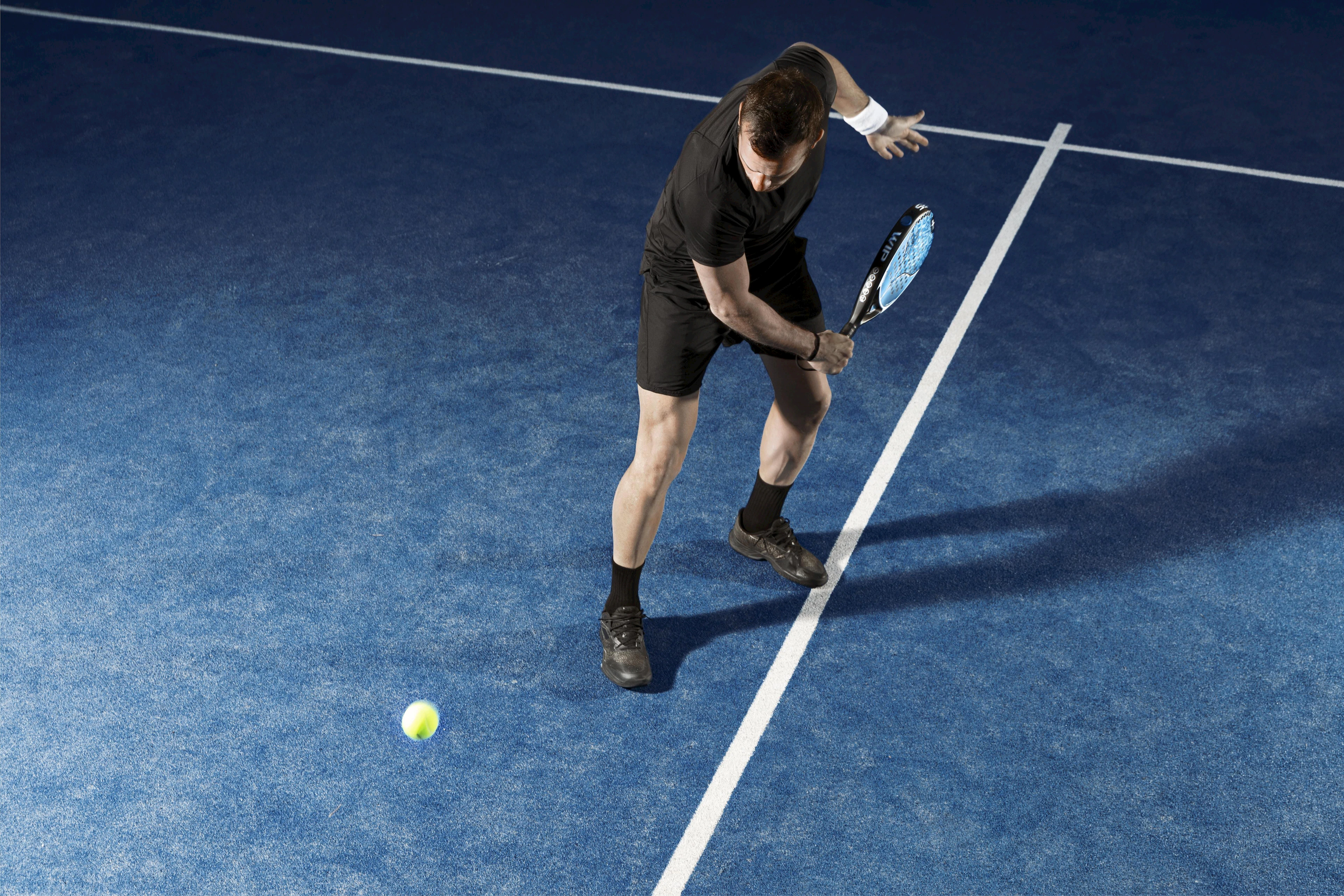 Padel player on court mid-swing