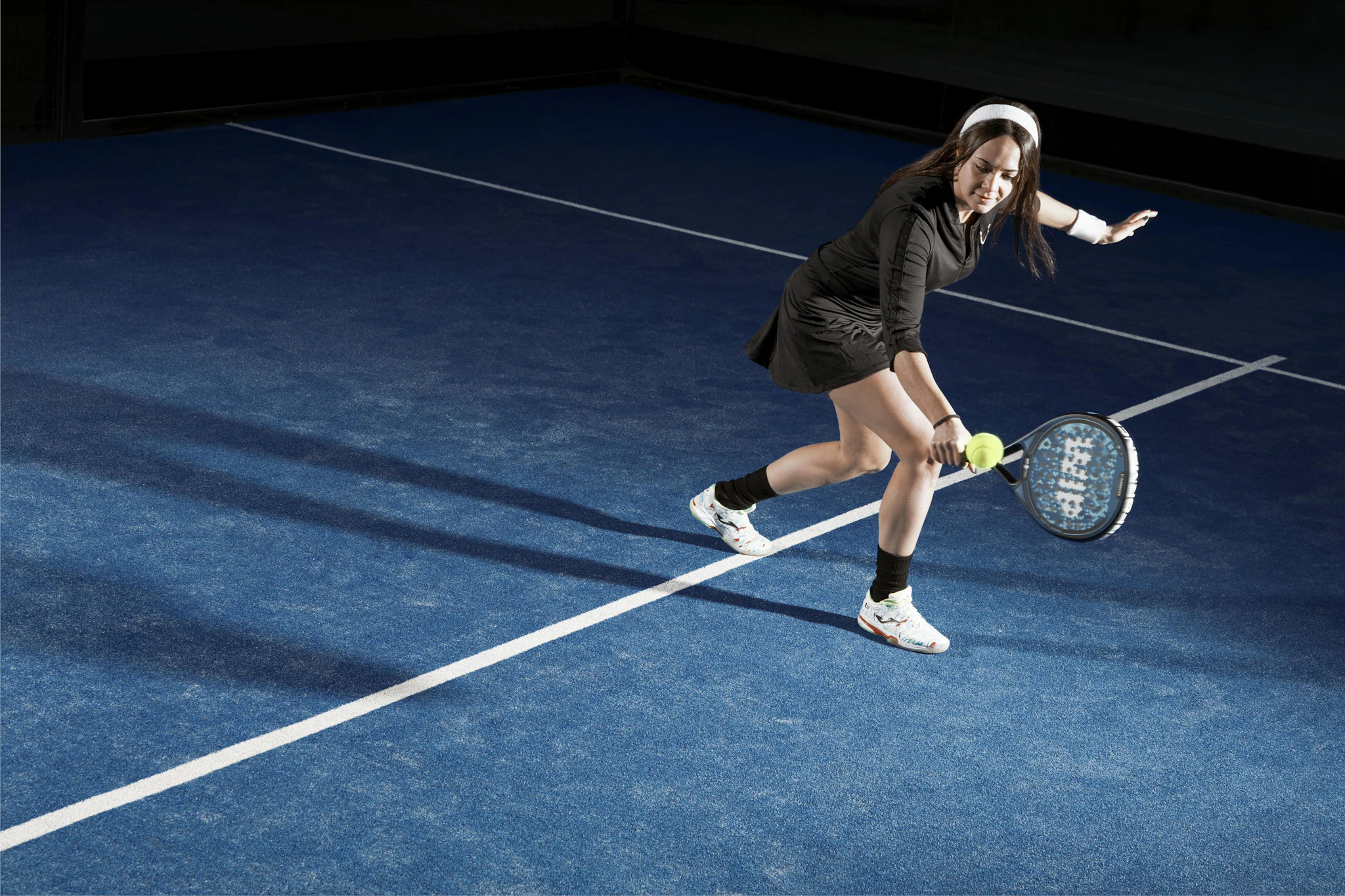 A padel player lining up a forehand on a blue court