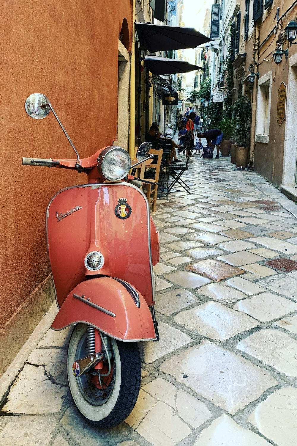 a red scooter parked on a cobblestone street