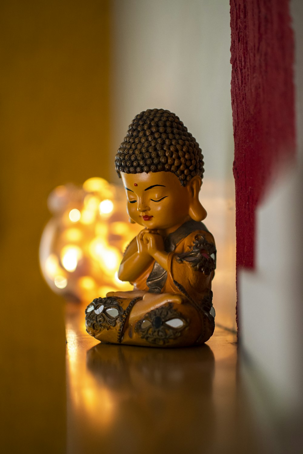 a buddha statue sitting on a table next to a candle