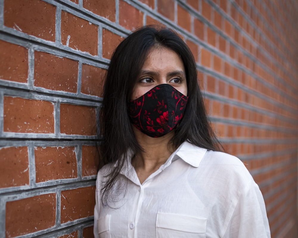 a woman wearing a face mask against a brick wall