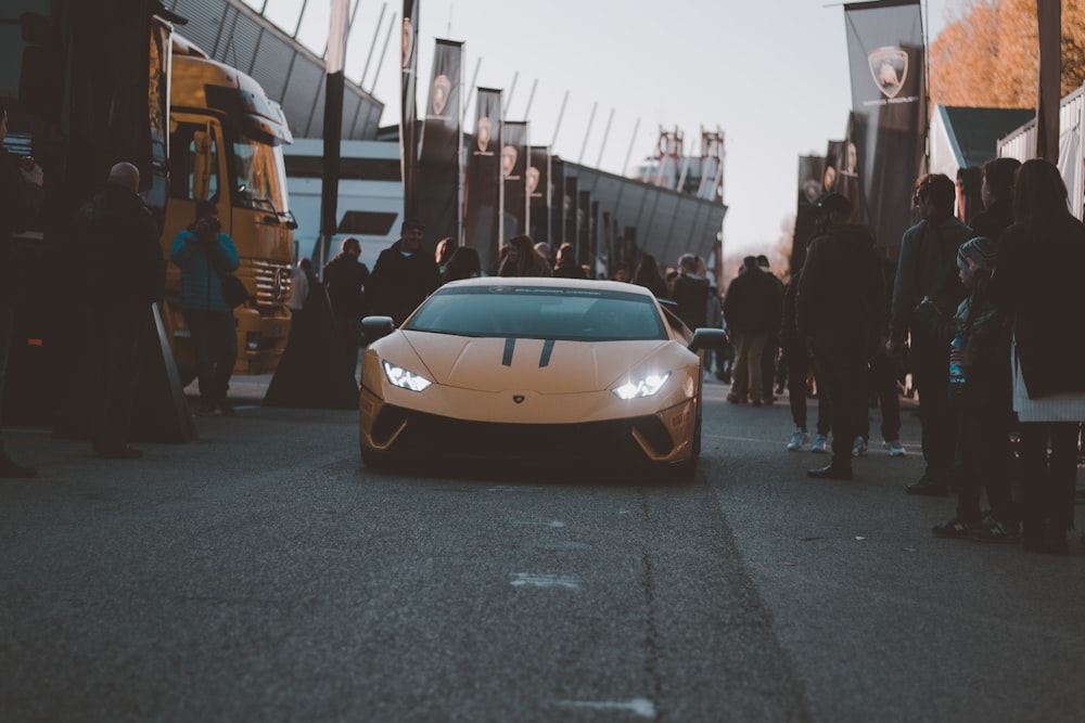 a white sports car parked in front of a crowd of people