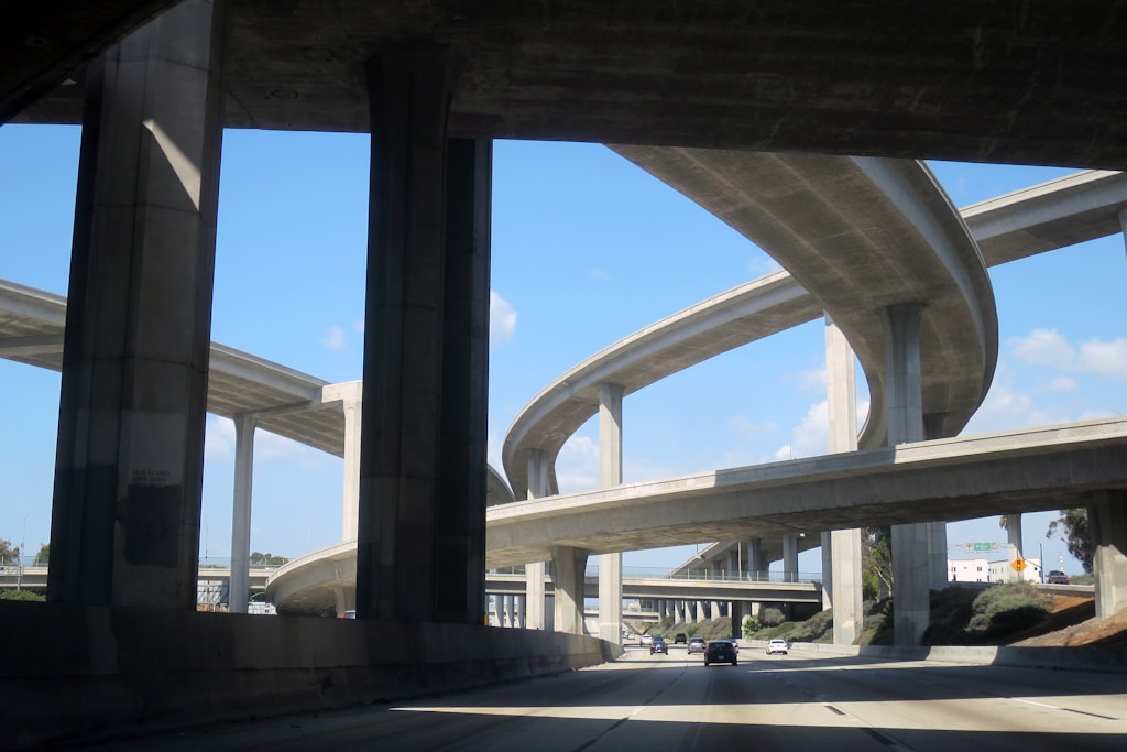 Get a driver's-eye view of other cars driving along the 110 Freeway in Los Angeles as they pass under the soaring interchange with the 105 Freeway. This is quintessential L.A. architecture and a typical view for thousands of people every commute.  Another sunny day in paradise.