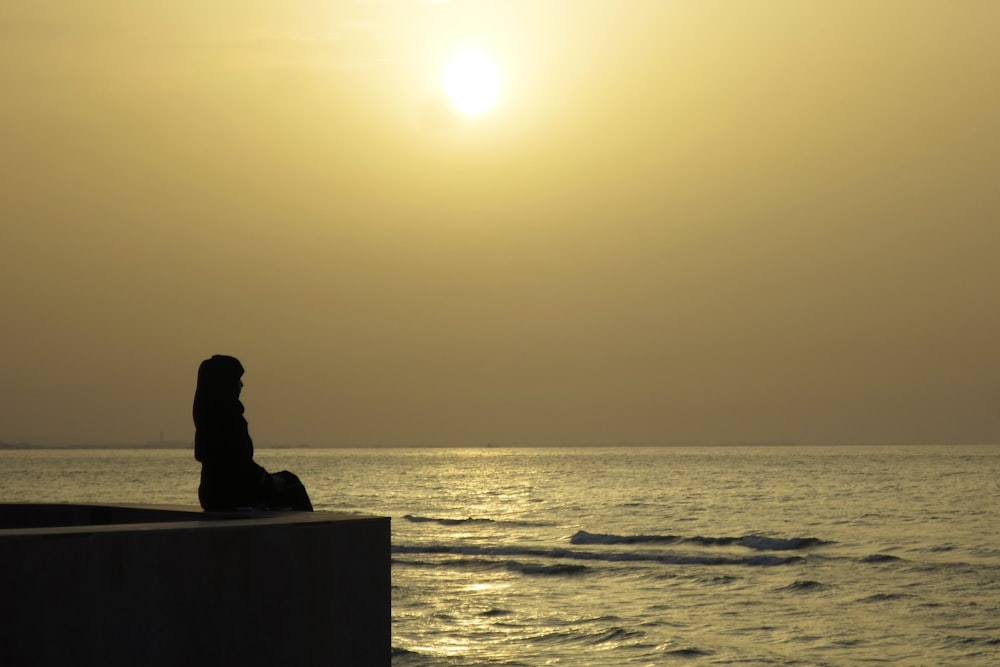 a person sitting on a wall looking out at the ocean