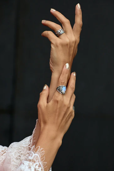 Close-up of a hand adorned with delicate rings and a flowing fabric sleeve.