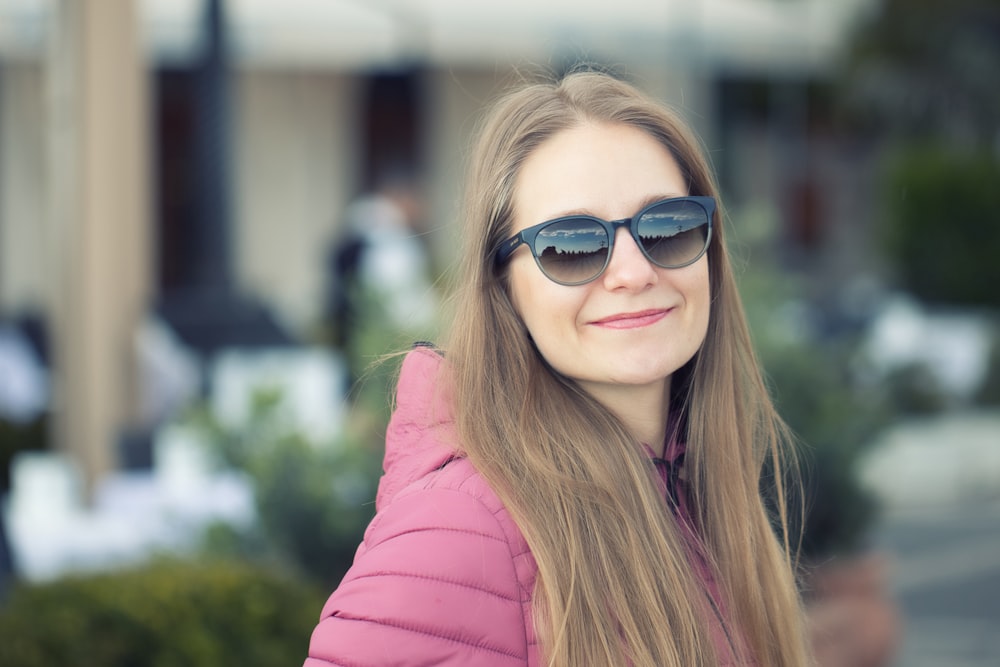 a woman wearing sunglasses and a pink jacket